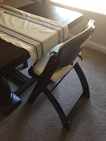 Reviewer's photo of the high chair pulled up close to the dining table