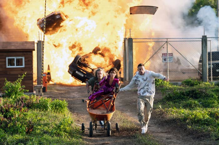 Brad Pitt carries Sandra Bullock in a wheelbarrow and Channing Tatum runs alongside with cars exploding in the background
