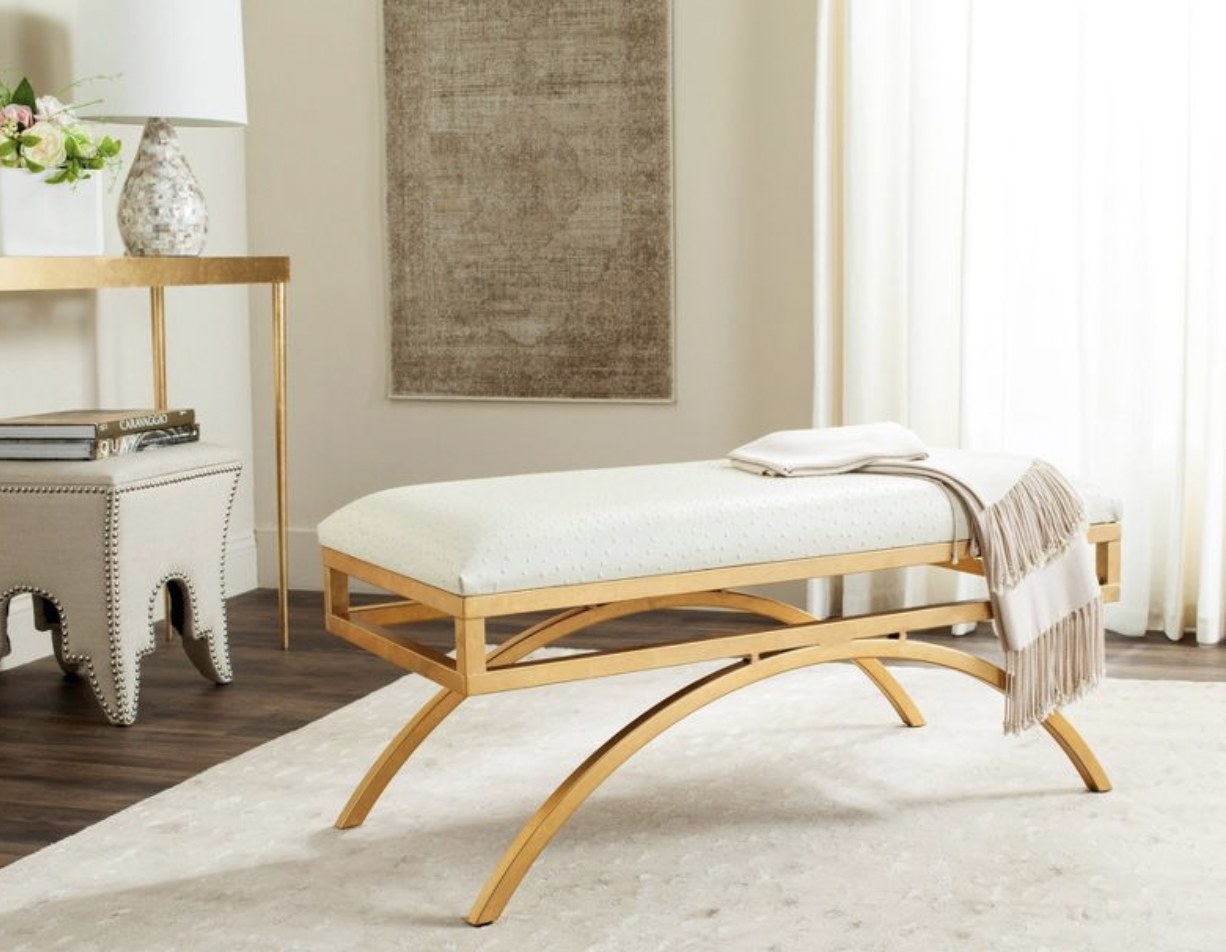 A white arc bench with gold legs.