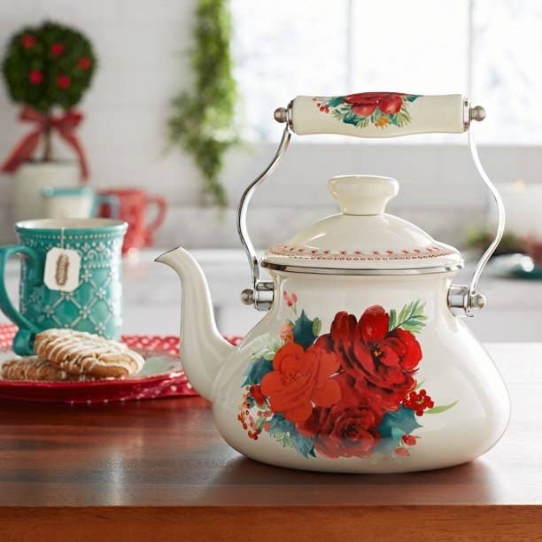 the white tea kettle with a red rose on t