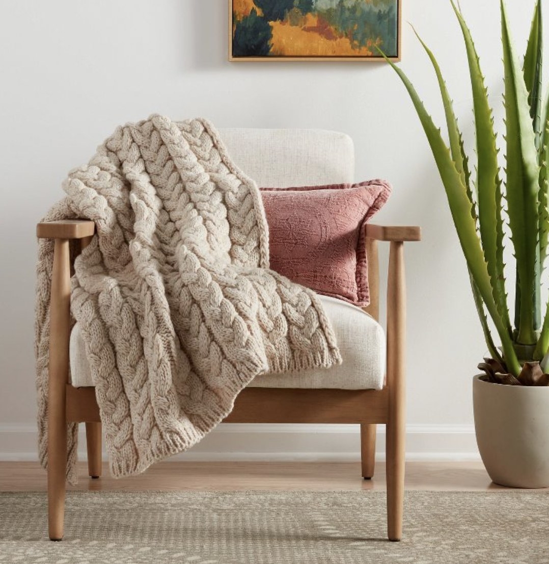 A beige cable knit throw blanket.