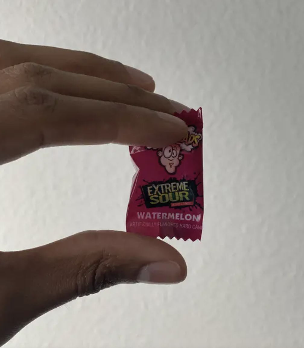 a small candy wrapper showing a cartoon face with the head blowing off from the sourness