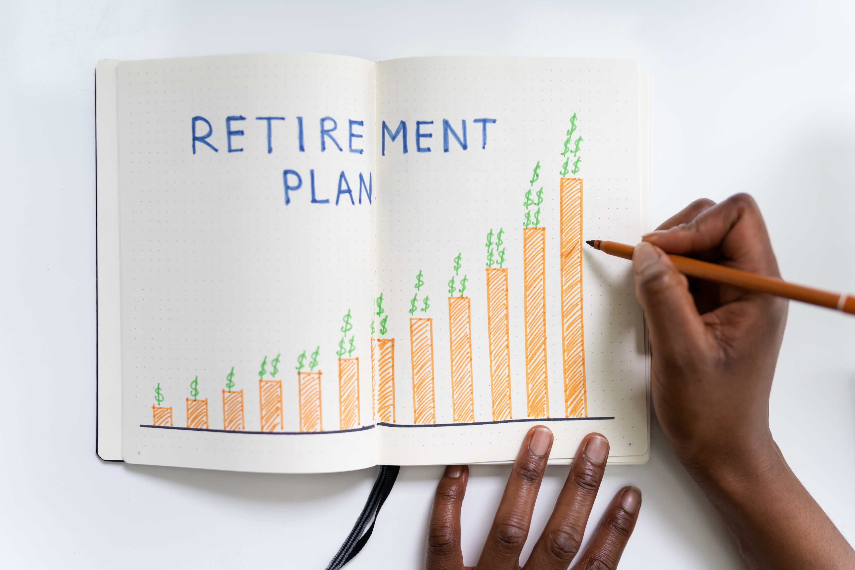 Person sketching a graph of their retirement savings plan in a journal