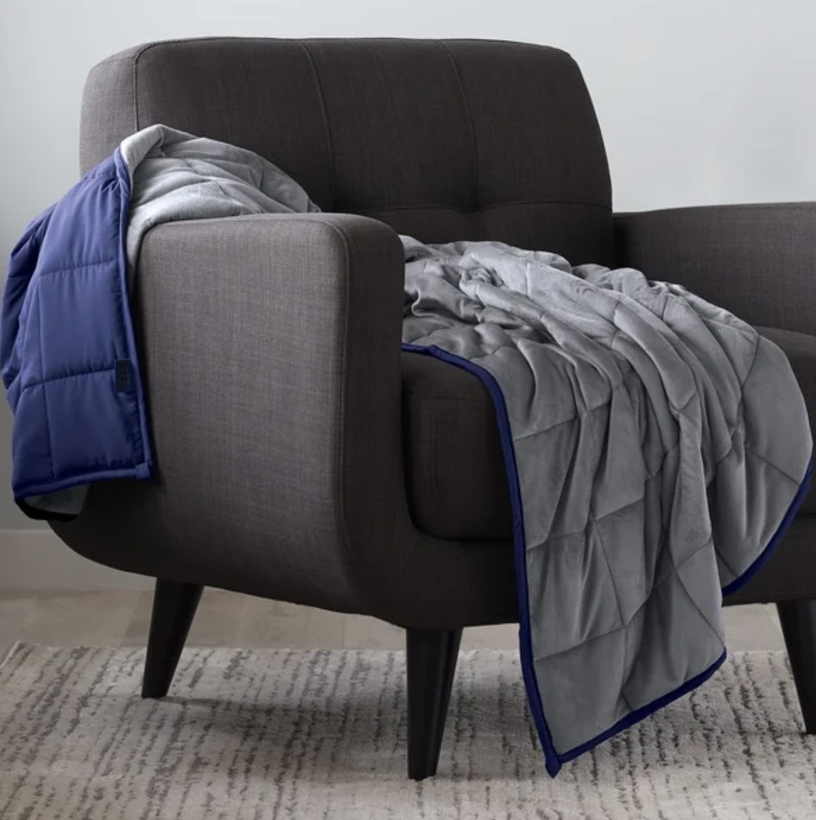 The reversible blanket has a gray side and a dark blue side and is draped across a dark chair