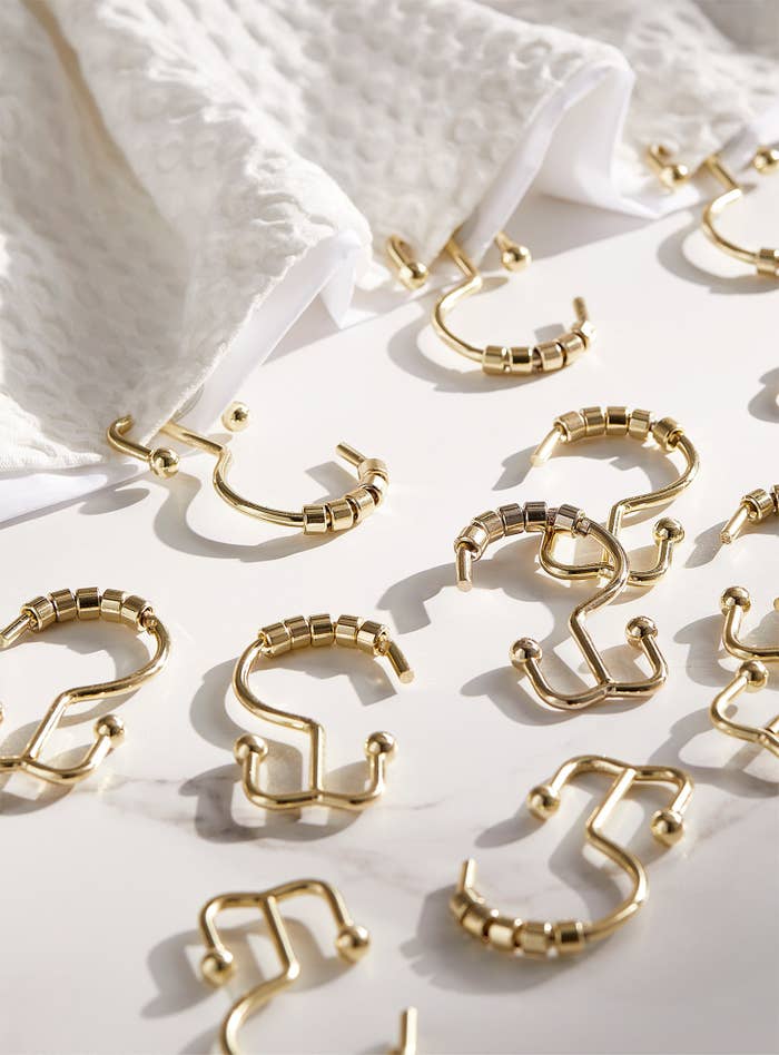 The hooks scattered across a flat surface with a shower curtain and liner nearby
