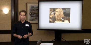 A close up of Dennis Reynolds as he does a PowerPoint presentation calling Dee ugly
