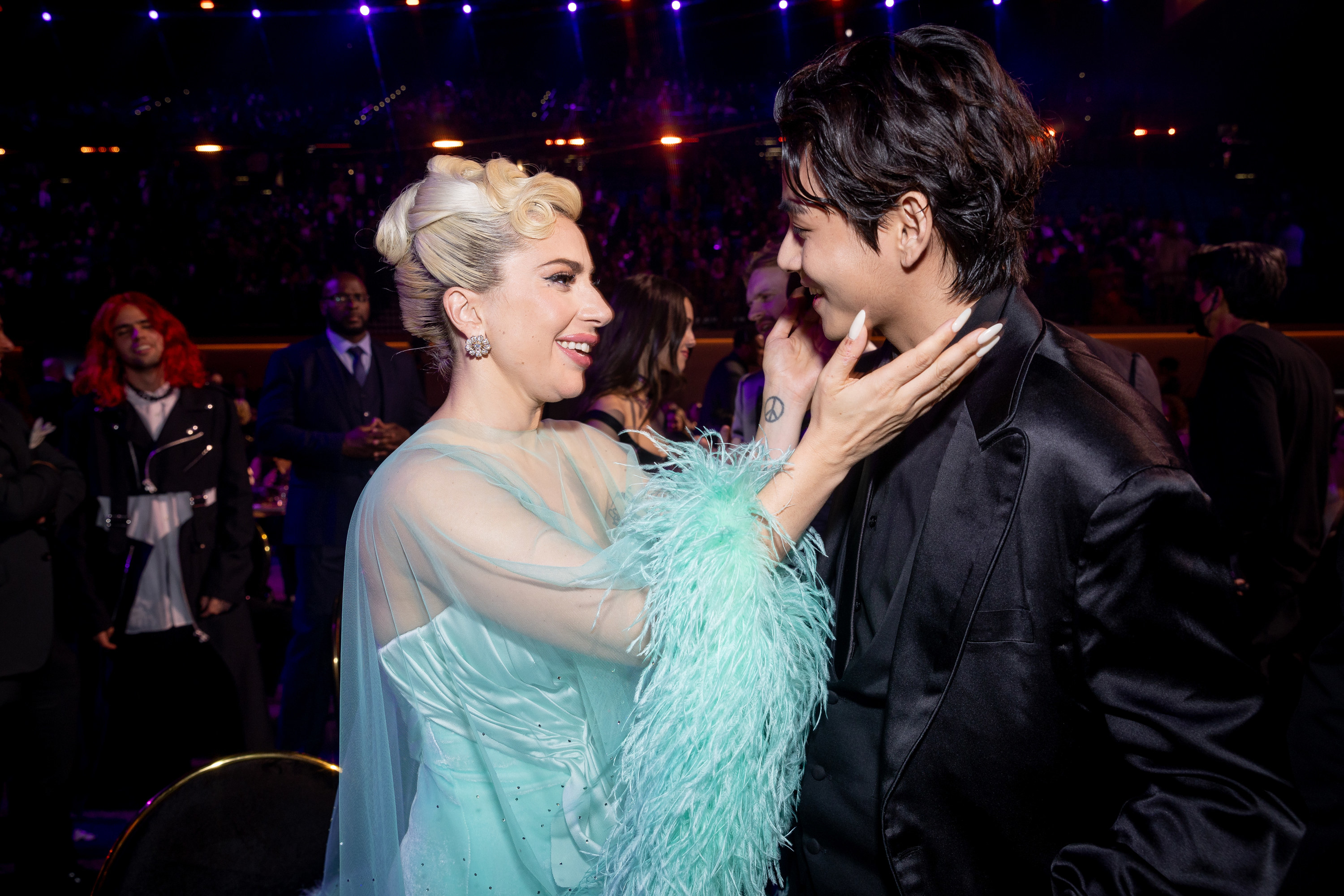 Lady Gaga talking with a member from BTS at the 2022 Grammys.