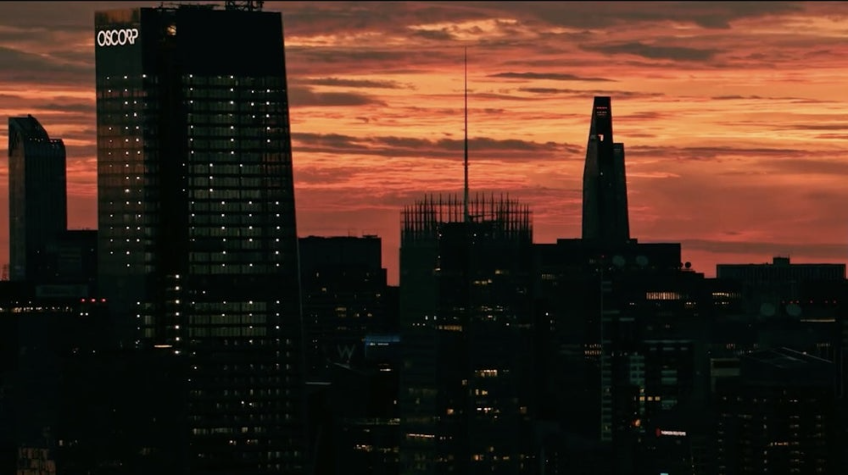 The Oscorp building on the left with other city buildings in the skyline visible in front of an orange sky