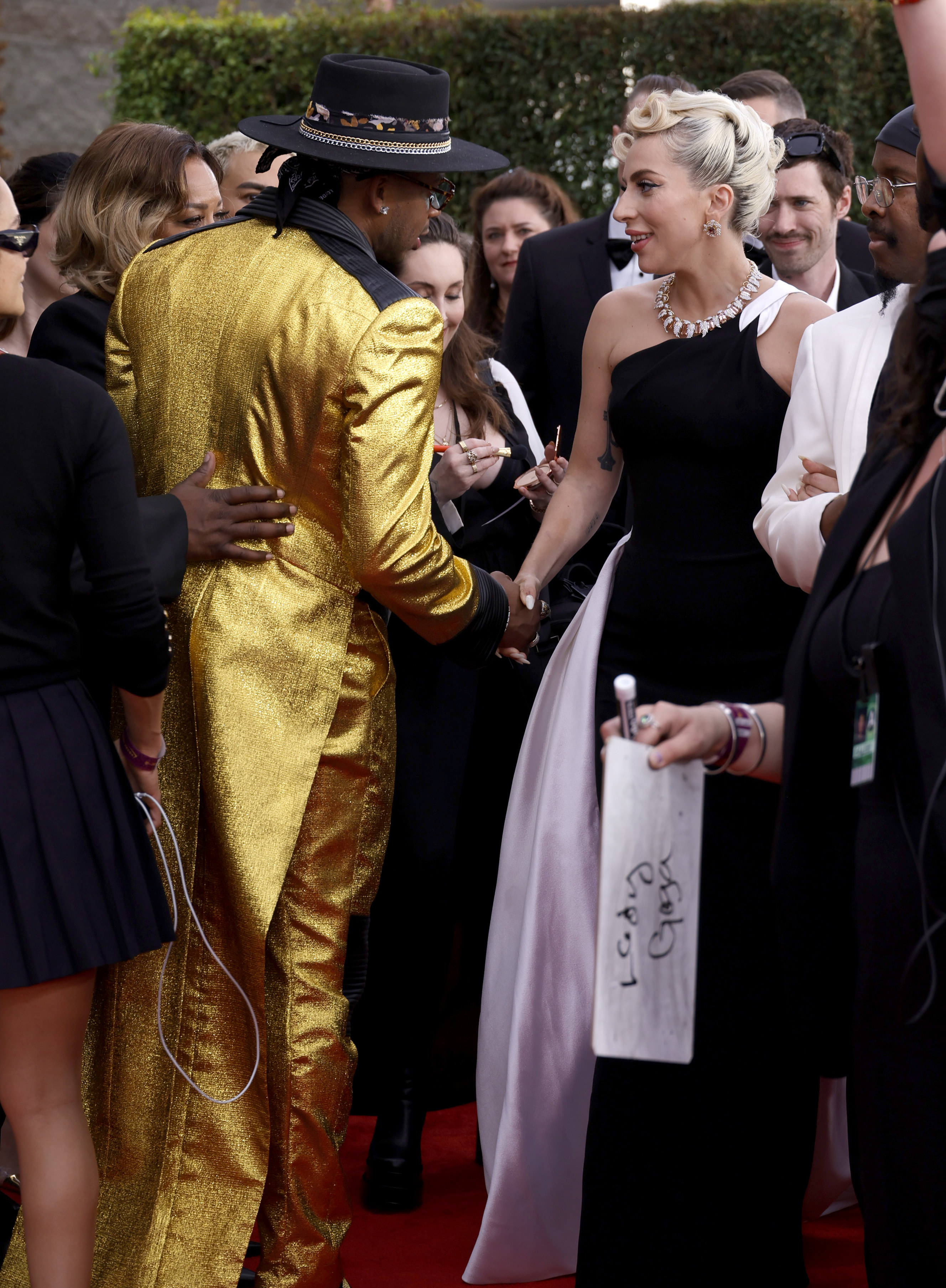 Lady Gaga shaking hands on the 2022 Grammys red carpet.