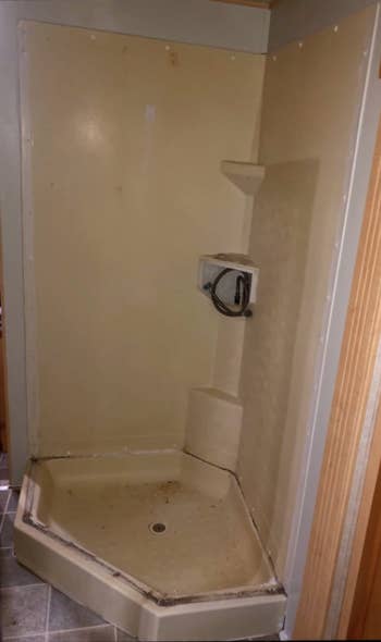 yellowed dingey and moldy looking shower surround and floor