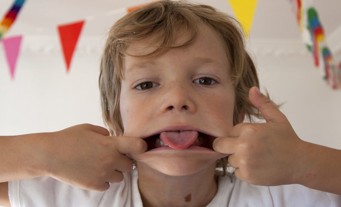 A little kid stretching his lips and sticking out his tongue.