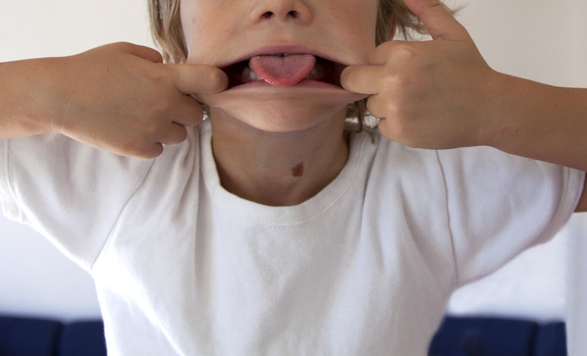 A little kid stretching his lips and sticking out his tongue.