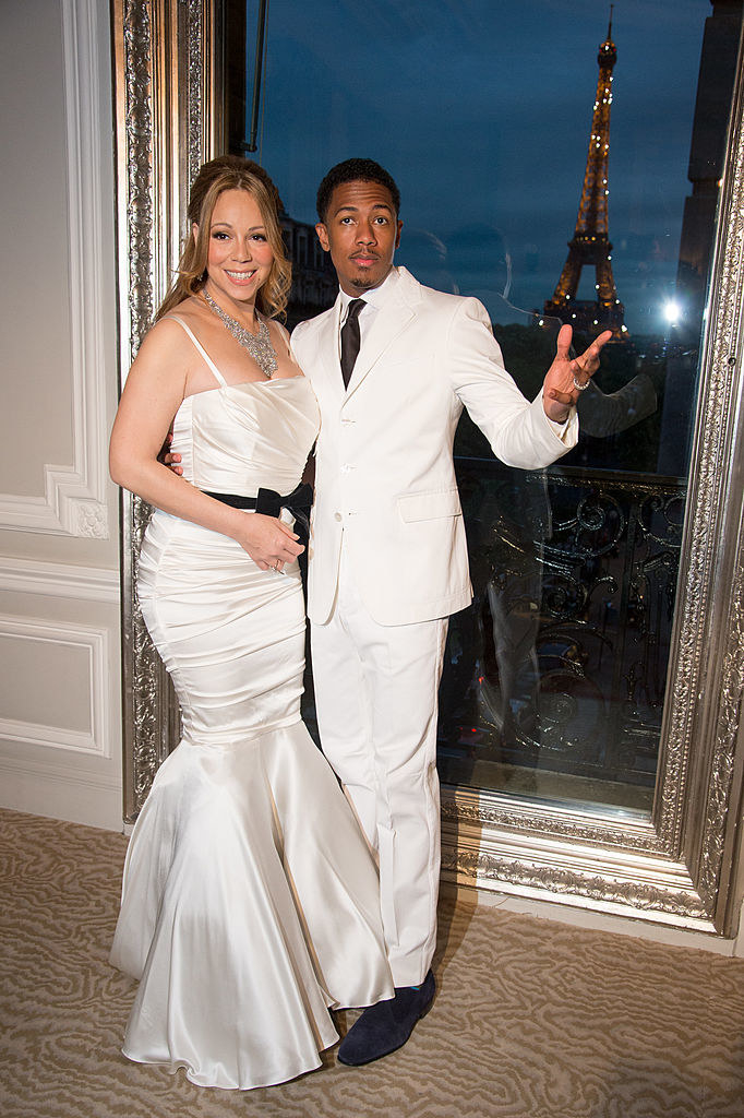 Mariah wears a mermaid cut wedding dress as the two pose by a window with the Eiffel tower in the background