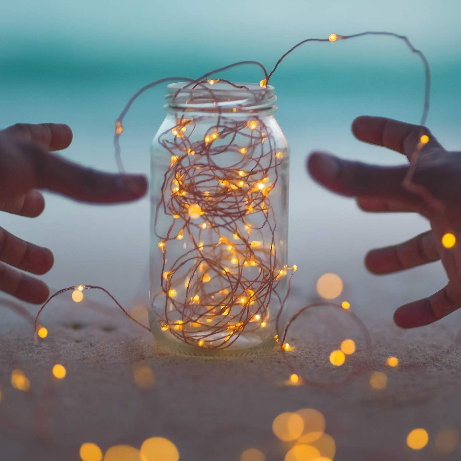 a person reaching for a jar filled with the solar powered fairy lights