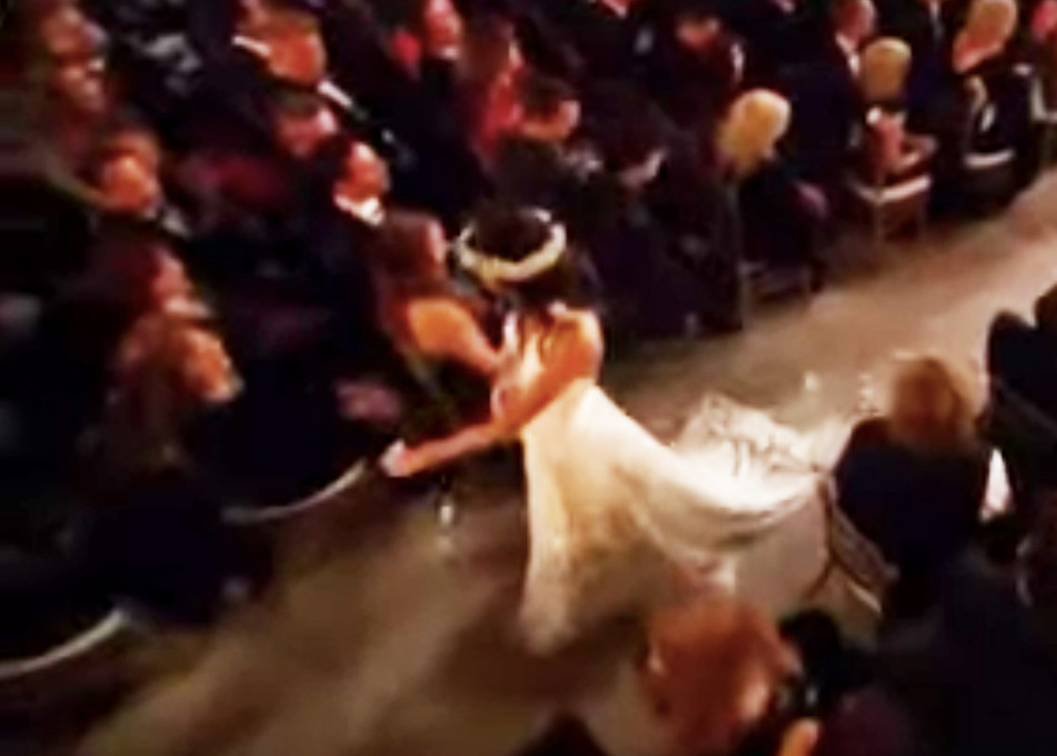 an aerial shot of a model in a white dress walking down the aisle
