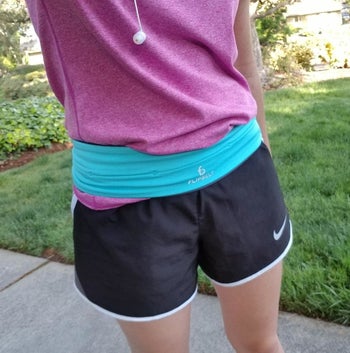 close-up of reviewer in quick-dry black Nike shorts and pink tank top wearing blue FlipBelt around hips
