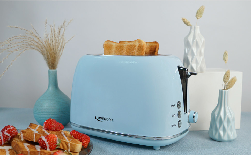 The toaster with two slices of toast popped, next to monochromatic decor and a plate of toast and strawberries