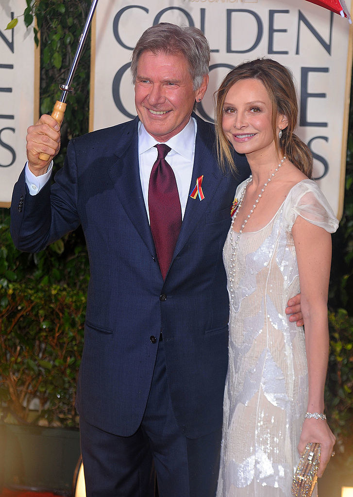 the two pose at the Golden Globes while Harrison holds up an umbrella