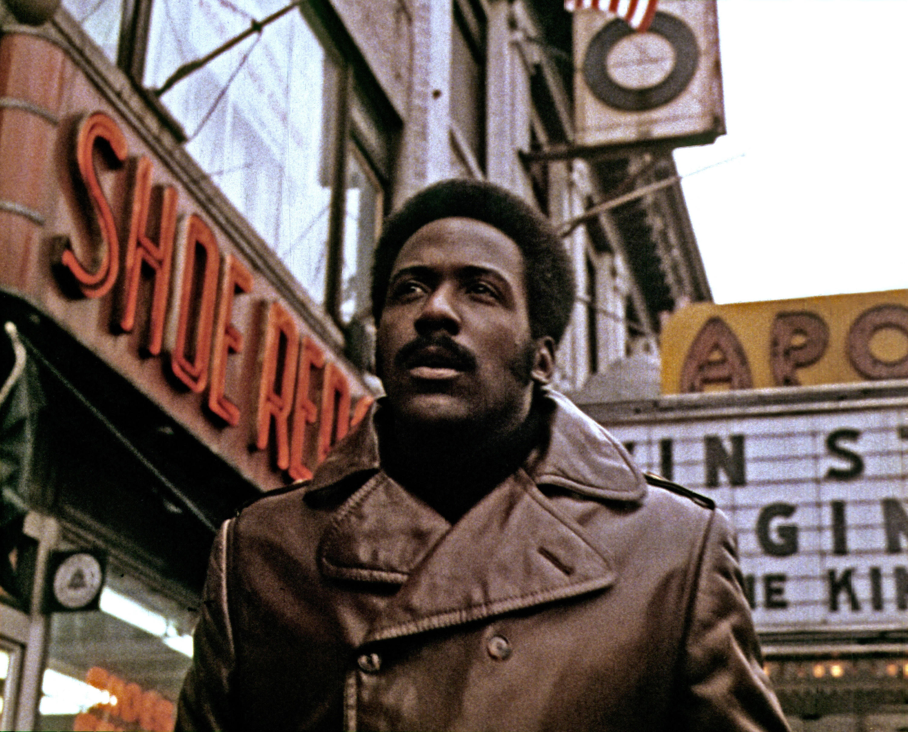 Richard Roundtree with a mustache and leather coat walking down 42nd Street
