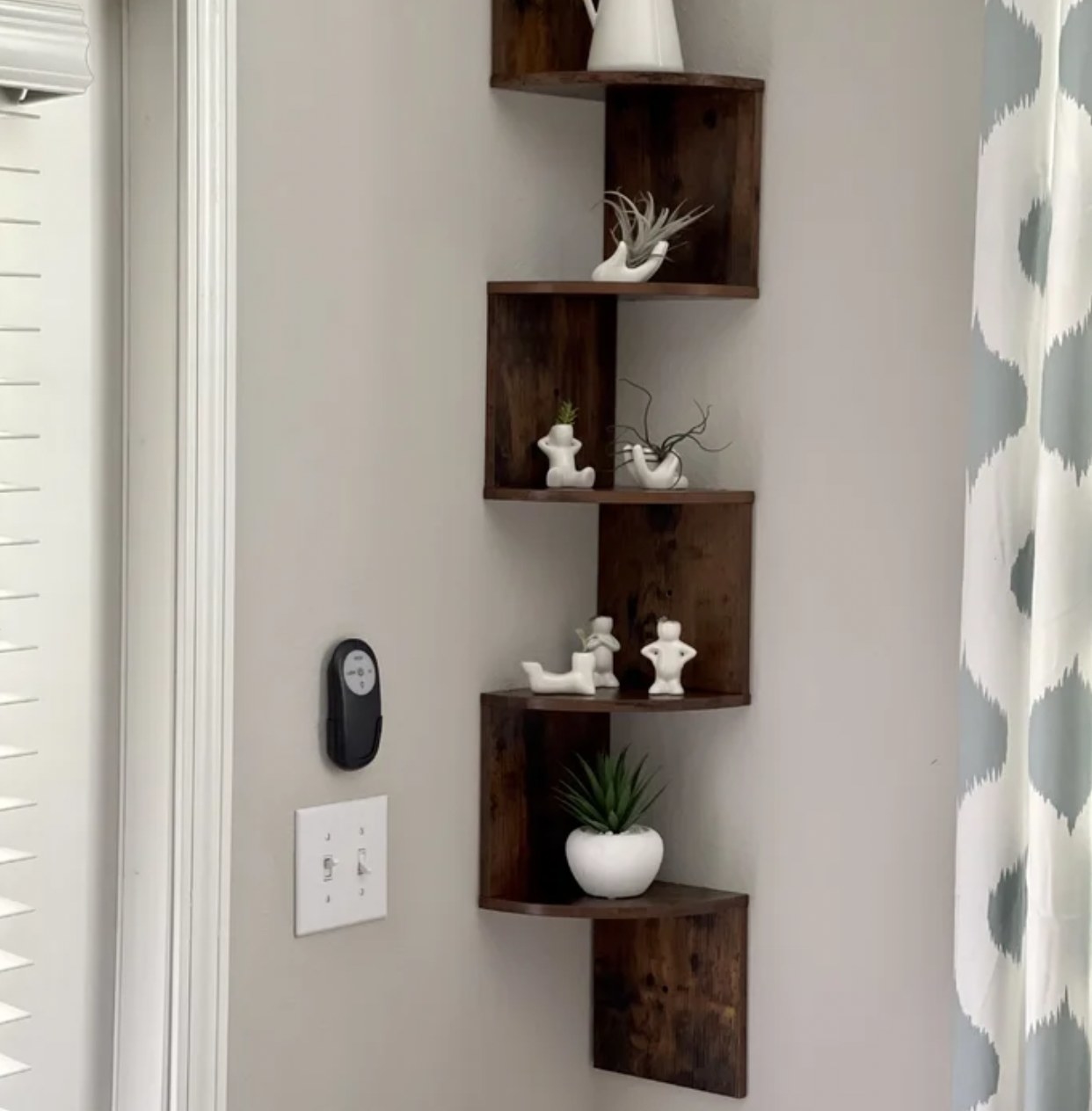 reviewer&#x27;s photo of the brown corner shelf holding various decorations and knick knacks