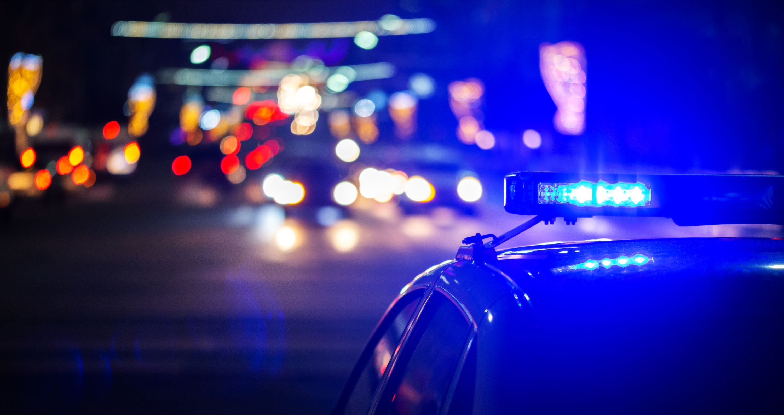A police car drives down the street with its lights on