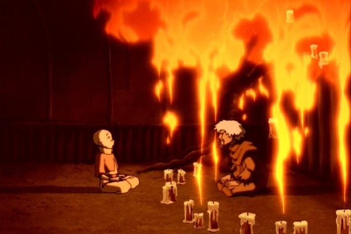 a young boy and old man sit cross legged in front of a row of candles, but there are giant flames above their heads