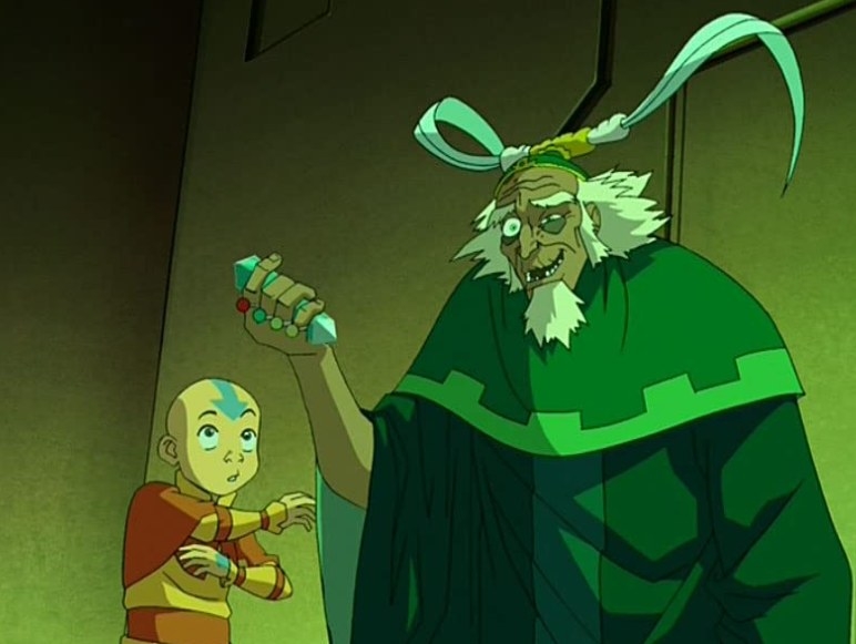 a young boy with an arrow on his bald head looks up, eyes wide and mouth in a circle. next to him is an old, tall man with a headband that has horns on it. he has a long beard and one eye is twitching.