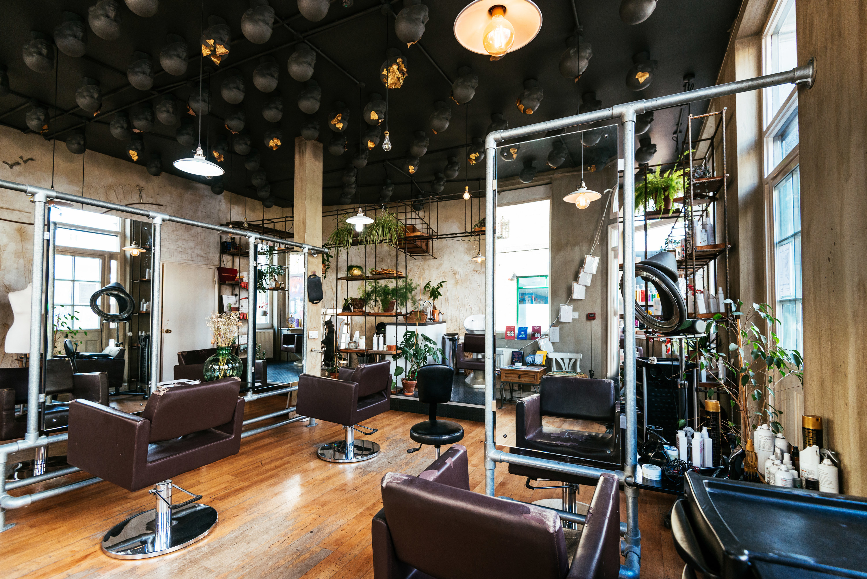 an empty hair salon with large mirrors and plants everywhere
