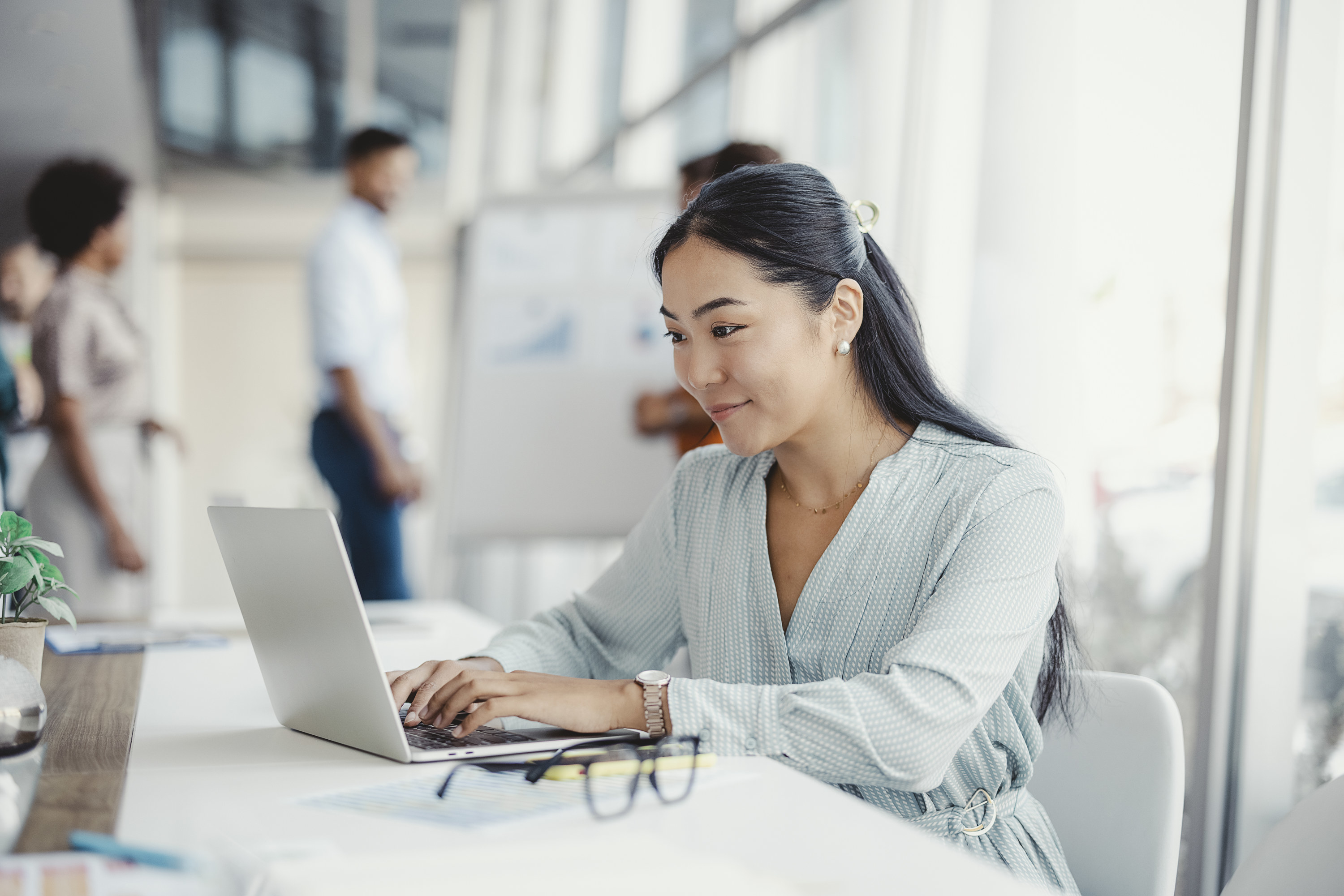 A woman sitting at a desk typing on her laptop