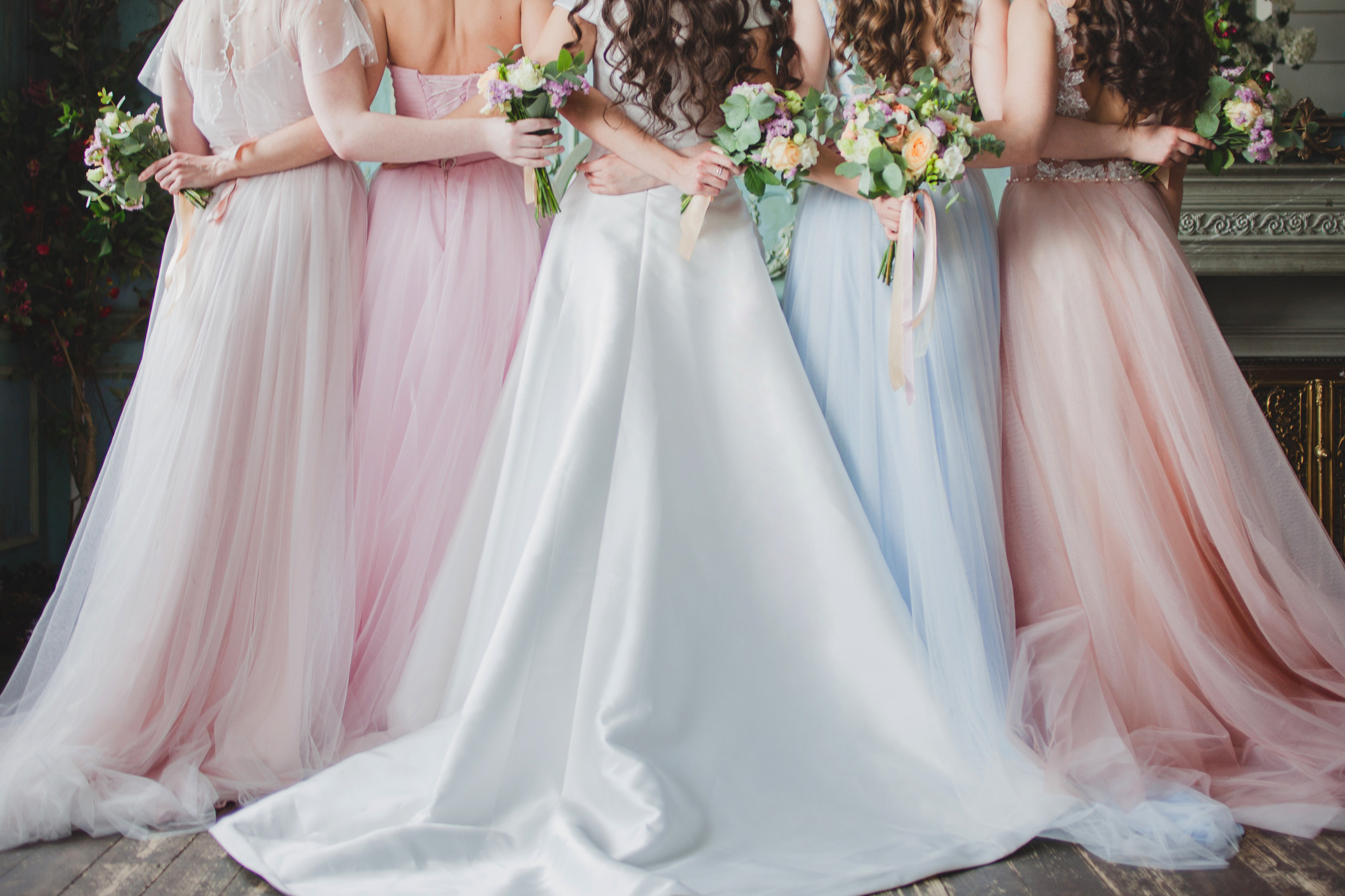 A group of bridesmaids embracing while holding bouquets.