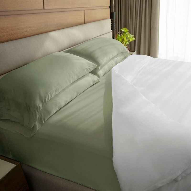 A made bed with four pillows and a duvet pulled back