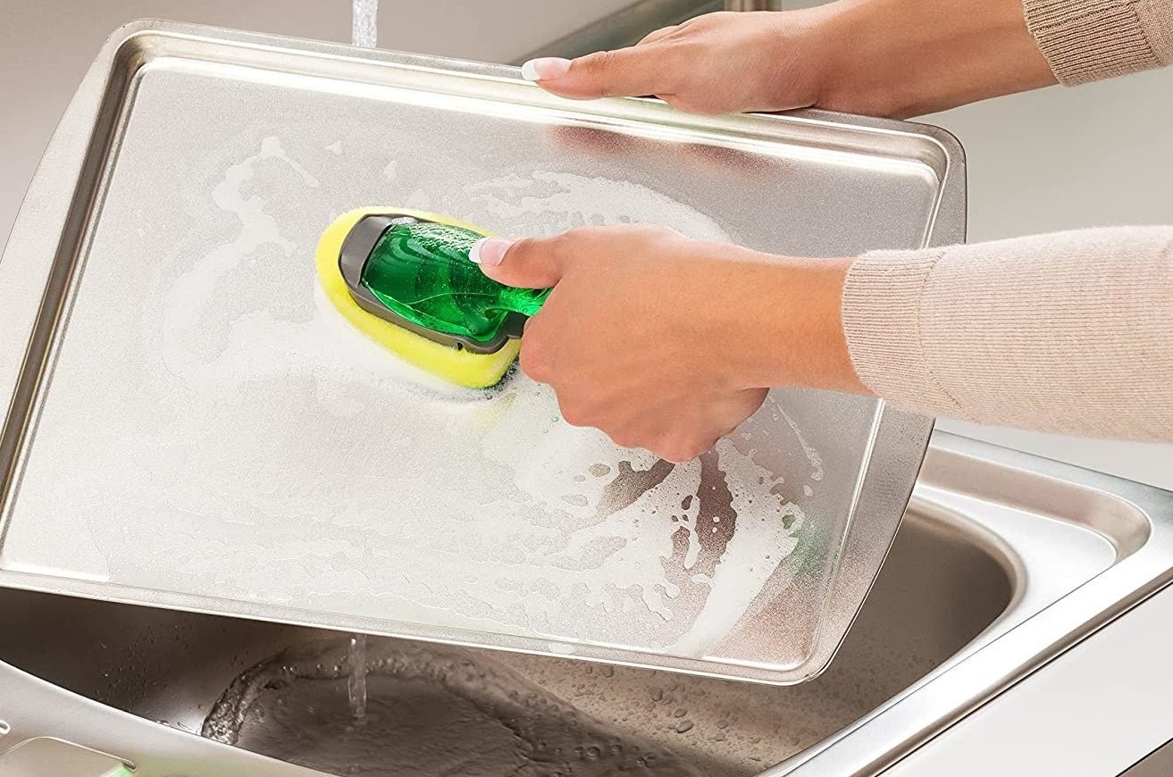 A person washing a cookie tray