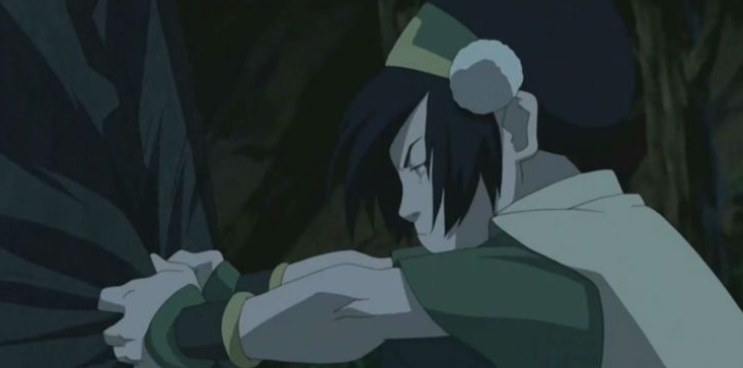 toph is a young adult girl with wispy hair and a thick headband with a pom pom on the side