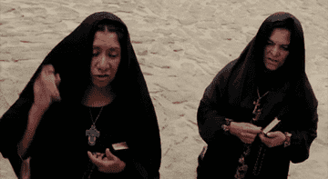 Two nuns splashing holy water while saying a prayer
