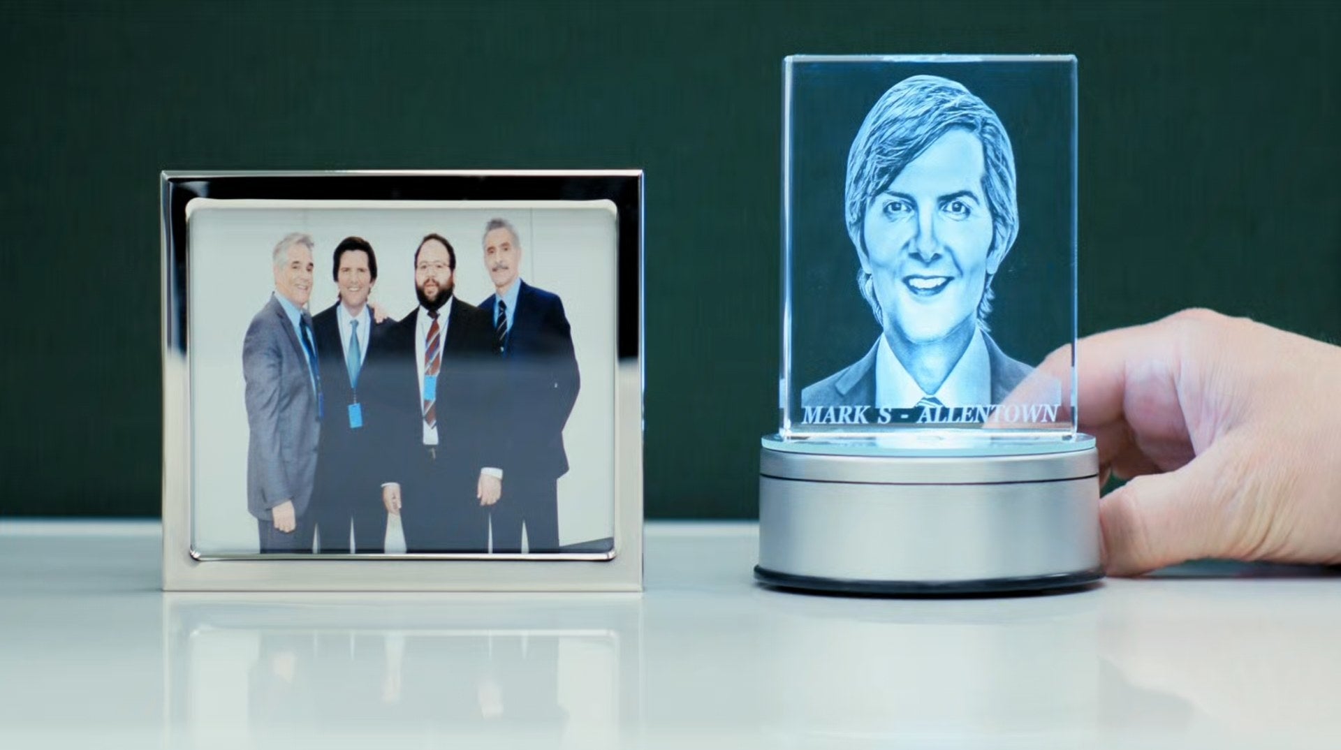 Adam Scott adjusts a memento with his photo kept next to a group photo of him with his colleagues