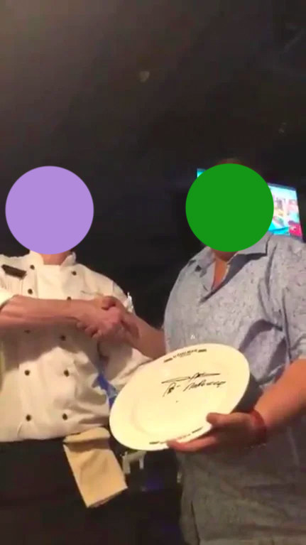 The individual with the signed plate, shaking hands with someone else