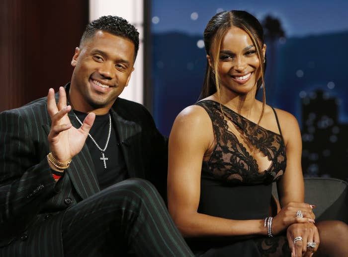 Russell waves to the audience while sitting next to Ciara
