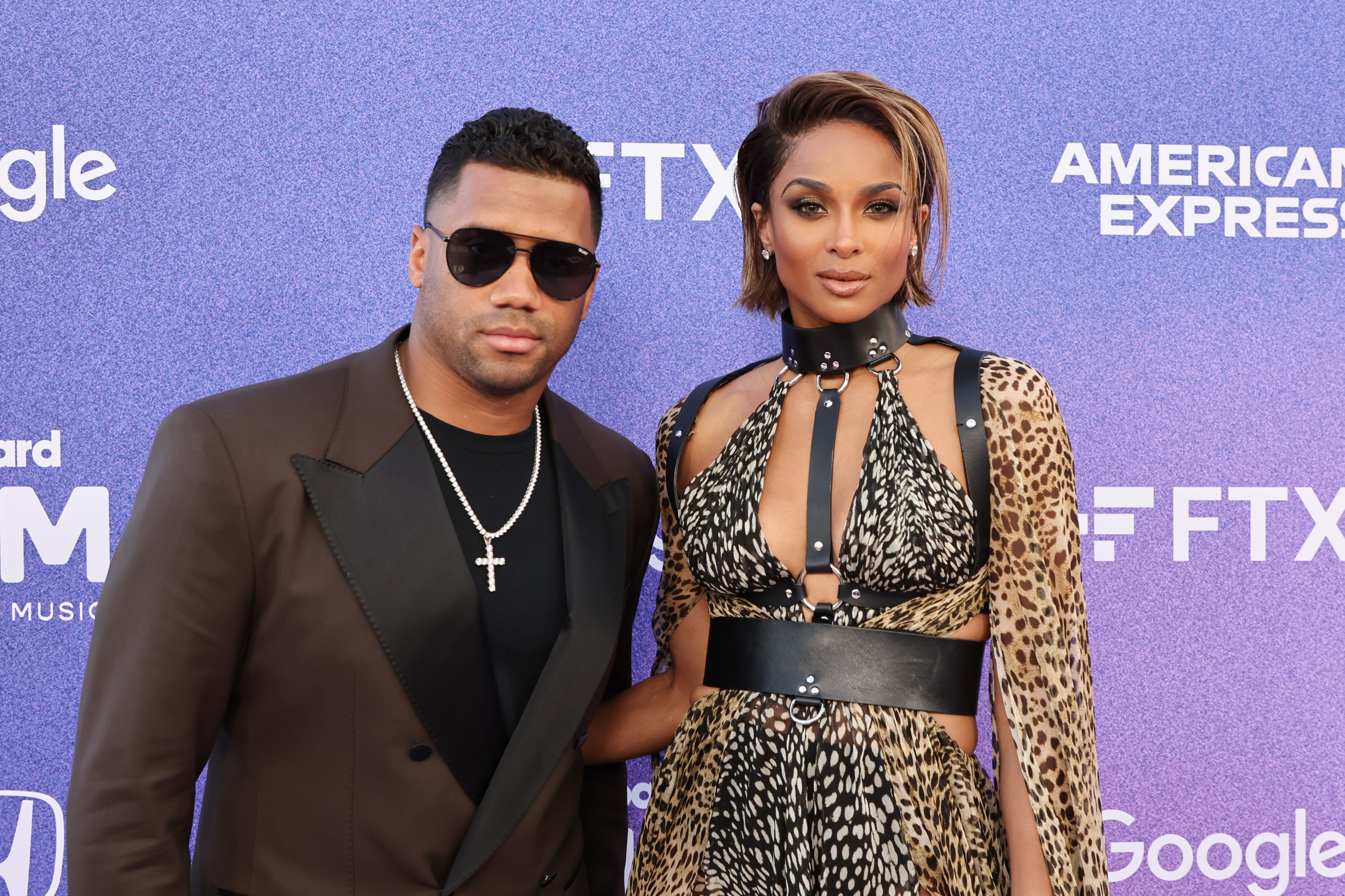 Russell and Ciara pose together at a step-and-repeat