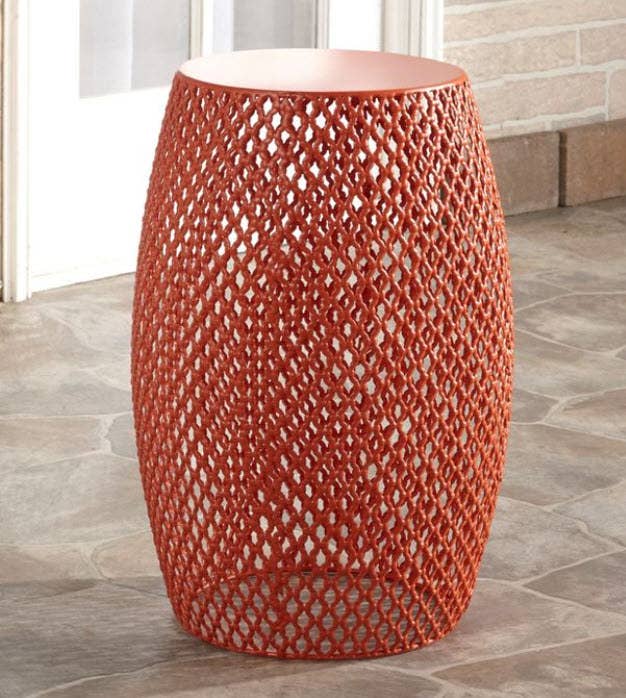 A cylinder shaped and hollow accent table with metal cage design.