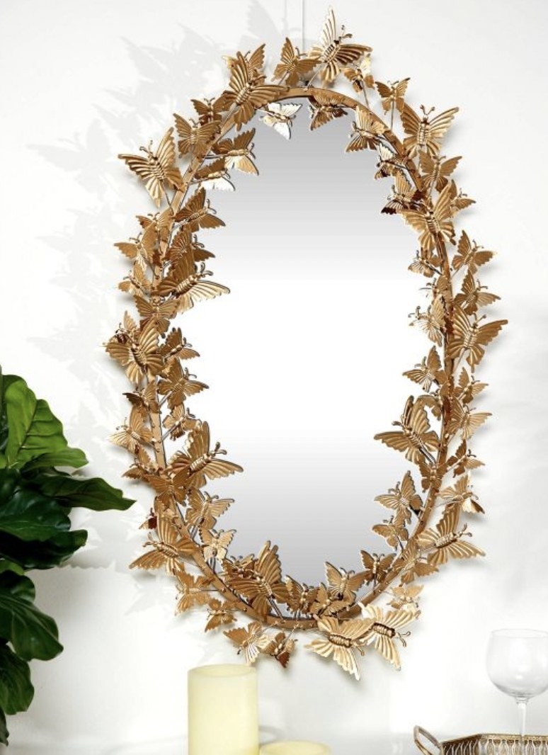 A gold oval mirror with 3D gold butterflies along the frame.