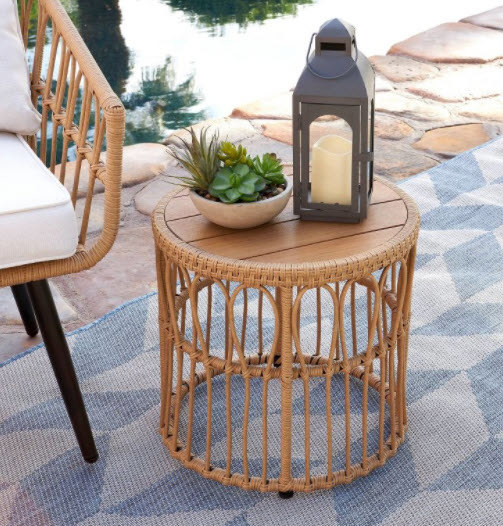 An adjustable boho style side table with circular top and wooden/wicker body.