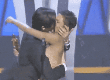 Adrien Brody wraps his arms around Halle Berry and kisses her onstage