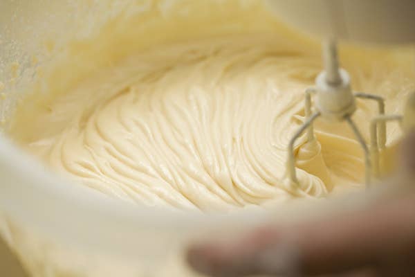A close-up of a person mixing cake batter with an electric hand mixer
