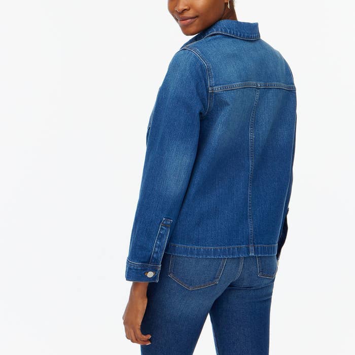 An image of a model wearing a blue denim jacket with pockets and button closure