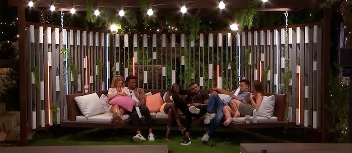 a group of contestants cuddle on the outdoor swing
