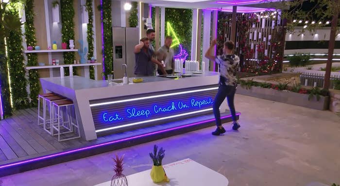 some of the male contestants hanging around the outdoor kitchen