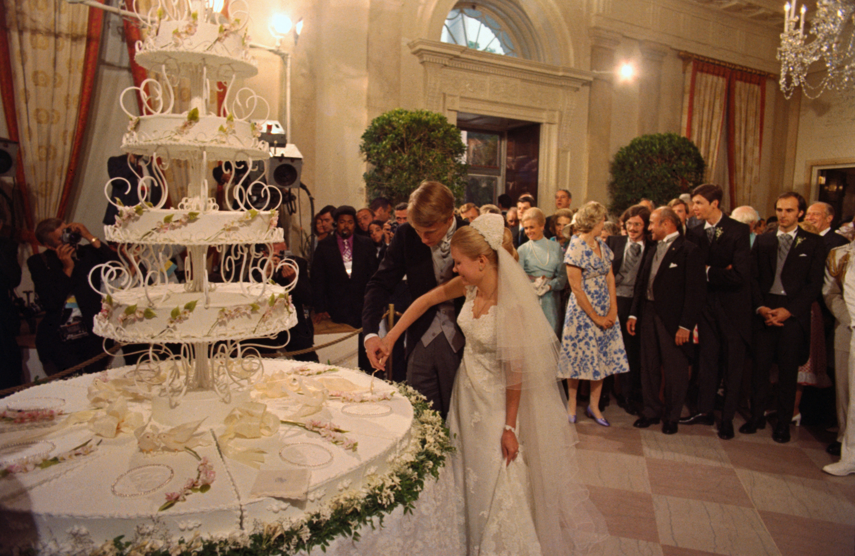 At the wedding of Edward Finch Cox and Tricia Nixon, the bride and groom cut the wedding cake as guests look on