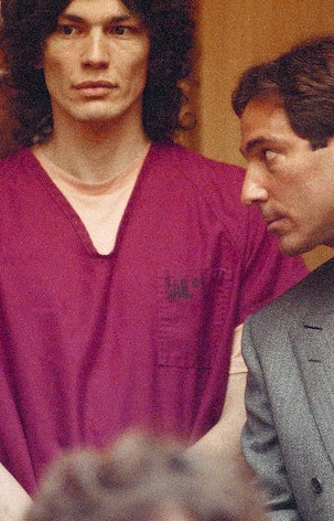 Richard with long curly hair wearing a prison uniform