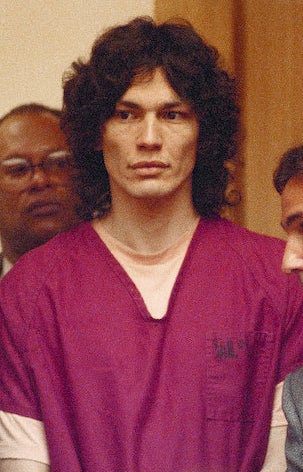 Richard with long curly hair wearing a prison uniform