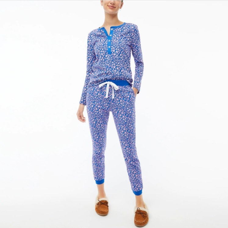 An image of a model wearing a pair of cotton Henley pajamas with a floral print